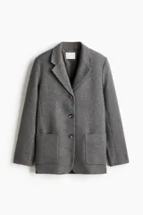 Blazer de botonadura sencilla en mezcla de lana color gris. Modelo con solapas de muesca, hombreras y bolsillos de parche delanteros. Cuenta con cierre de botones en el frente y forro interior.