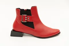 Botín de cuero negro con elásticos laterales, aplique metálico con ojales y cierre lateral con cremallera. Taco cuadrado desfasado de 3 cm.