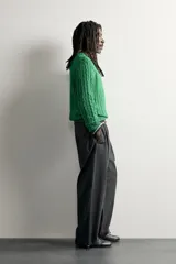 Sweater de punto verde con diseño de trenzas, cuello redondo y manga larga, de corte regular fit y acabados en rib.