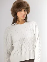 Sweater de punto con diseño de ondas en relieve y tejido con hilo de lurex que aporta un brillo sutil. Presenta cuello redondo, mangas largas y terminaciones en rib acanalado.