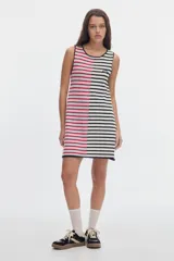 Vestido midi de punto sin mangas con diseño de rayas, corte evasé. Presenta un diseño bicolor asimétrico: el lado izquierdo con rayas horizontales blancas y rojas sobre fondo celeste, y el lado derecho con rayas horizontales negras y blancas. Incluye un pequeño parche bordado en el pecho.