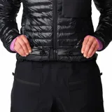 Campera acolchada de mujer Mountain Hardwear, color negro, con cierre frontal, cuello alto, bolsillo en el pecho y puños elásticos con detalle en color lila.