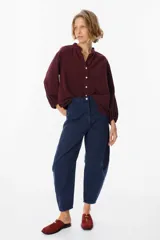 Camisa de pana color verde oliva, con cuello mao, cierre frontal de botones y mangas largas abullonadas con puños elásticos.