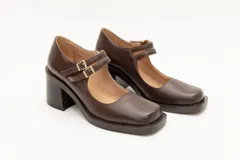 Guillerminas de cuero charol negro con punta cuadrada, taco ancho y correa sobre el empeine con doble hebilla dorada.