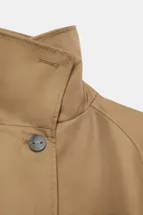 Chaqueta corta de cuello subido y manga larga con trabilla y botón. Cuenta con bolsillos de vivo en el delantero y cierre frontal con botones.