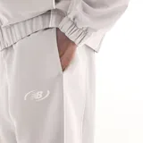 Pantalón deportivo New Balance de hombre, modelo Trackside, color gris con cintura elástica, puños ajustados en los tobillos y pequeño logo bordado en la pierna izquierda.