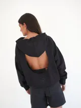 Buzo negro oversize de felpa con capucha y espalda descubierta, mangas largas, calce relajado y detalle de logo bordado en la parte inferior.