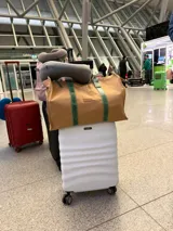 Bolso tipo tote bag de lona color beige, con asas de cuero verde.