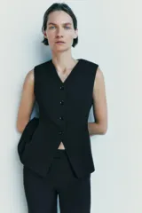 Chaleco negro entallado de Zara Woman Collection, con escote pico, sin mangas, forro interior a tono, bajo asimétrico y cierre frontal con botones.