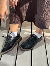 Zapatillas de cuero negro con cordones y suela marrón.