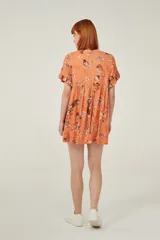 Vestido corto de viscosa con estampado floral en tonos verdes, rojos y blancos. Presenta un diseño holgado con cuello a la base y mangas cortas con volados en los extremos.