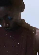 Top sin mangas de tejido de punto con brillos, diseño entallado y cuello alto con detalle de fular largo integrado.