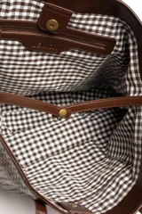 Bolso tipo shopper color marrón de cuero sintético con diseño trenzado. Cuenta con doble asa de hombro y placa metálica con el logo de la marca en el frente.