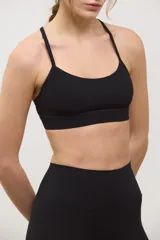 Top deportivo negro de compresión media, con escote redondo clásico, tiras finas cruzadas en la espalda y tazas intercambiables.