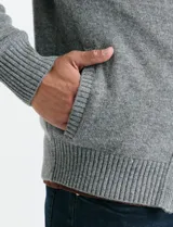 Cardigan de punto gris con cuello alto, cierre frontal de metal con doble cursor y bolsillos laterales. Presenta puños y cuello en tejido canalé.