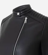 Campera biker de poliuretano color verde oliva, con cierre frontal asimétrico, bolsillos laterales con cremallera y detalle capitoneado en los hombros.