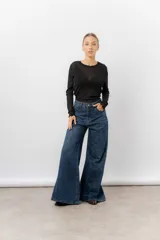 Jean de tiro alto con corte wide leg y pierna amplia. Confeccionado en denim rígido de lavado azul clásico, cuenta con bolsillos funcionales y cierre frontal.