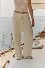 Pantalón de tejido de punto color off white, de corte recto y holgado. Presenta cintura elástica con cordón de ajuste y acabado en rib.