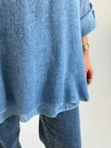 Sweater de punto color azul jean, con cuello redondo, mangas largas con vuelta y diseño amplio de corte evasé.