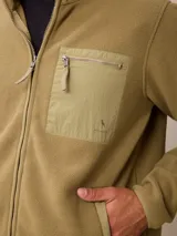 Campera de polar color verde militar, con cierre frontal completo, cuello alto y bolsillo en el pecho con cierre y detalle en tela técnica.