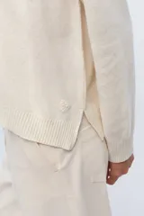 Sweater de tejido de punto color beige, con escote en V y calce holgado.