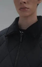 Campera oversize de microfibra opaca con diseño matelaseado de rombos. Presenta cuello de corderoy a tono, cierre frontal metálico y dos amplios bolsillos delanteros con solapa y broche snap. Interior forrado y relleno con guata térmica.