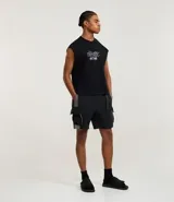 Bermuda masculina de estilo baggy, color negro, con cintura elástica, cinturón ajustable y bolsillo cargo con recortes en color gris contrastante. Confeccionada en poliéster.