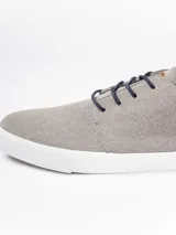 Zapatilla urbana de gamuza sintética color gris, con cordones oscuros, suela de goma blanca y detalles en cuero sintético color suela en el talón y lateral.
