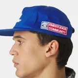 Gorra azul marino con visera curva y cierre ajustable en la parte posterior. Cuenta con un escudo bordado en hilo blanco en la parte frontal con la inscripción "EMESTUDIOS".