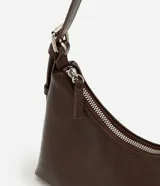 Cartera tipo baguette de tamaño pequeño en cuero sintético color bordó, con correa ajustable y cierre de cremallera metálica con herrajes en níquel.