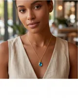 Collar de bronce con cadena fina de eslabones y un dije colgante en forma de lágrima con piedra azul translúcida en bisel dorado.