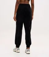 Pantalón tipo jogger de plush color negro, con cintura elástica, bolsillos laterales y puños ajustados en los tobillos.