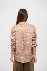 Camisa de manga larga con cuello camisero y cierre frontal de botones. Presenta un estampado de puntos irregulares en tonos tierra.