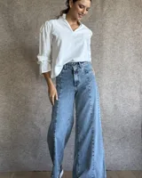 Jean de corte wide leg en color azul medio, con costuras verticales decorativas en el frente y diseño de tiro alto.