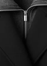 Abrigo largo de corte recto y diseño combinado, con cierre de doble botonadura, cuello camisero y dos bolsillos laterales. Cuenta con forro interior y manga larga.