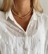 Gargantilla de mostacillas color lila con dije dorado en forma de candado.