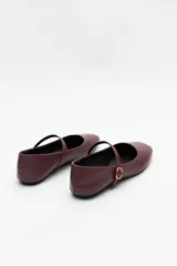 Balerinas color crudo de símil cuero texturizado, con punta redondeada, tira sobre el empeine y hebilla metálica ajustable.