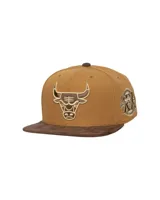Gorra de visera plana Mitchell & Ness de los Chicago Bulls, color marrón tostado con visera de gamuza marrón oscuro. Presenta el logo del equipo bordado en el frente y un parche conmemorativo en el lateral.