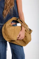 Cartera hobo grande de cuero descarne color marrón, con correa de hombro ajustable y cierre superior con cremallera.