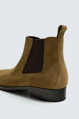 Bota estilo Chelsea fabricada en piel con acabado de serraje, cuenta con elásticos laterales para facilitar el calce, horma redonda y suela a contraste con un ligero tacón.