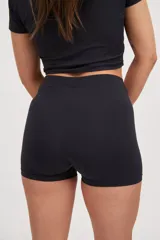 Calza corta negra ajustada al cuerpo, tiro medio, confeccionada en tejido suave con protección UV50+ y logo estampado al tono.