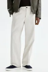 Pantalón sastrero de corte relajado en sarga color beige, con cierre y botón, bolsillos laterales y bolsillos traseros con botón oculto. Presenta piernas con pliegues.