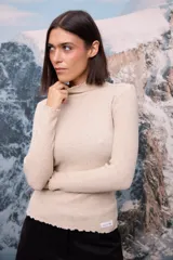 Polera de tejido de punto fino color blanco, con cuello alto, mangas largas y terminaciones con detalle de ondas en puños, cuello y ruedo.