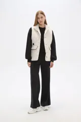 Chaleco acolchado de diseño capitoneado en color verde militar, con cuello alto, cierre frontal con botones a presión y bolsillos laterales con solapa y detalles en contraste.