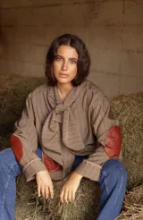 Blazer de corte oversize confeccionado en tela casimir a rayas, con cuello tipo lazo y parches de cuero en los codos y bolsillos frontales.