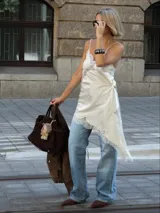Vestido slip dress corto de color beige, con tirantes finos, diseño asimétrico y detalles de encaje en el escote y el dobladillo.