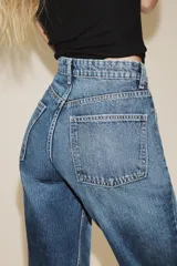 Jeans de tiro alto con diseño de cinco bolsillos, trabillas para cinturón y cierre frontal con cremallera y botón metálico.