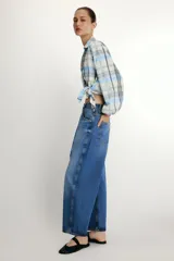 Jeans de tiro medio con diseño barrel, cinco bolsillos y cinturón fino del mismo tejido. Presenta pernera ancha en los muslos que se estrecha gradualmente hacia el tobillo, con cierre frontal de cremallera y botón.
