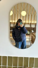 Campera puffer azul marino con estampado de motivos náuticos en blanco, rojo y verde.