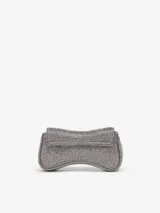 Cartera bandolera compacta Diesel Play Crossbody XS, de diseño curvo con acabado brillante plateado. Cuenta con el icónico logo Oval D en el frente y correa desmontable para llevarla cruzada o como clutch.